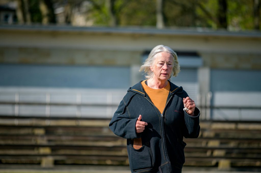 Elderly woman jogging on a bright day, showcasing active lifestyle and wellness in the urban outdoors.
