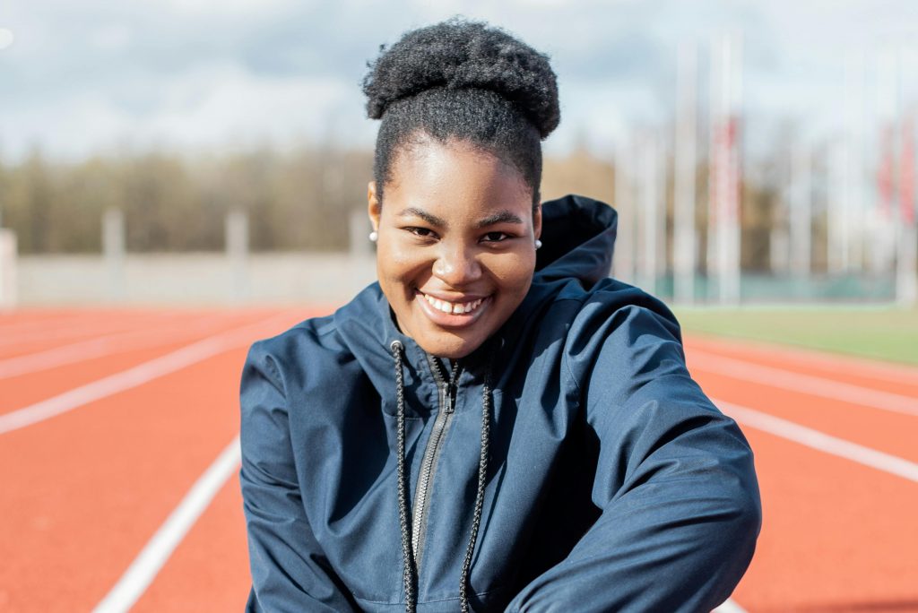 Portrait of a smiling woman on an outdoor running track in sportswear.